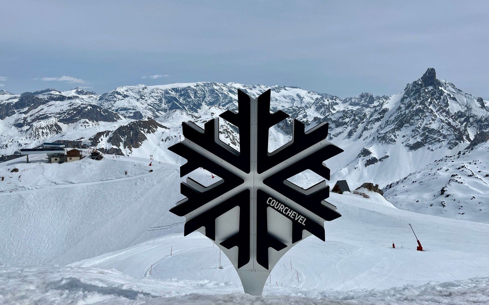 A large snowflake-shaped sculpture labeled Courchevel stands atop a snowy mountain ridge
